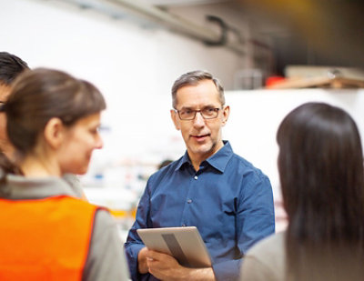 A man wearing glasses and a blue shirt holding a tablet.