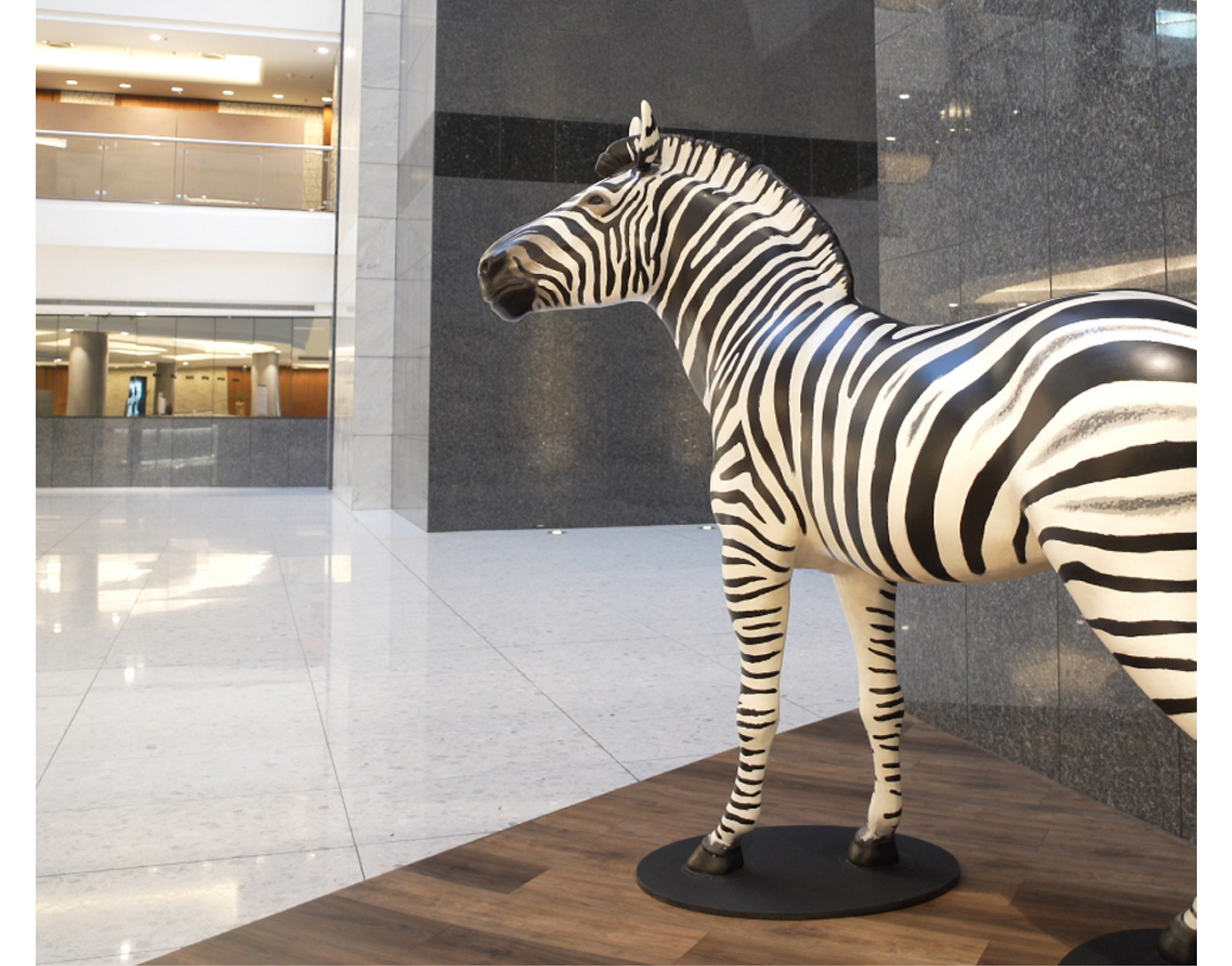 zebra sculpture in a modern building lobby with marble floors and tiered balconies in the background.
