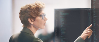 Person pointing at computer screen with code.