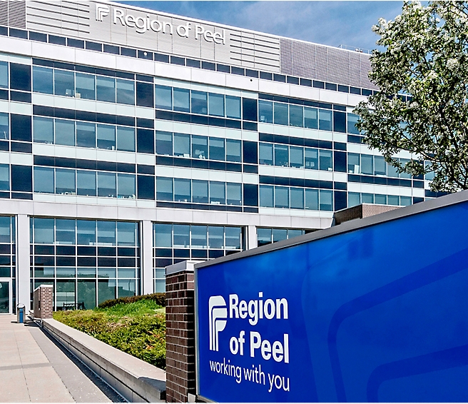 Außenansicht des Bürogebäudes von Region of Peel mit einem Schild im Vordergrund, auf dem steht: „Region of Peel – Working with you.“