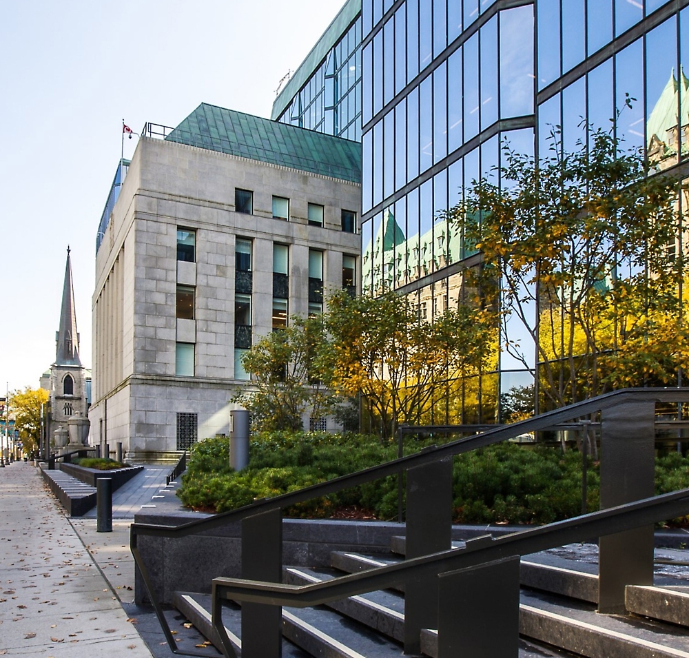 Cảnh quan đô thị hiện đại với tòa nhà xây bằng kính và đá cùng nhà thờ lịch sử hiển thị phía sau