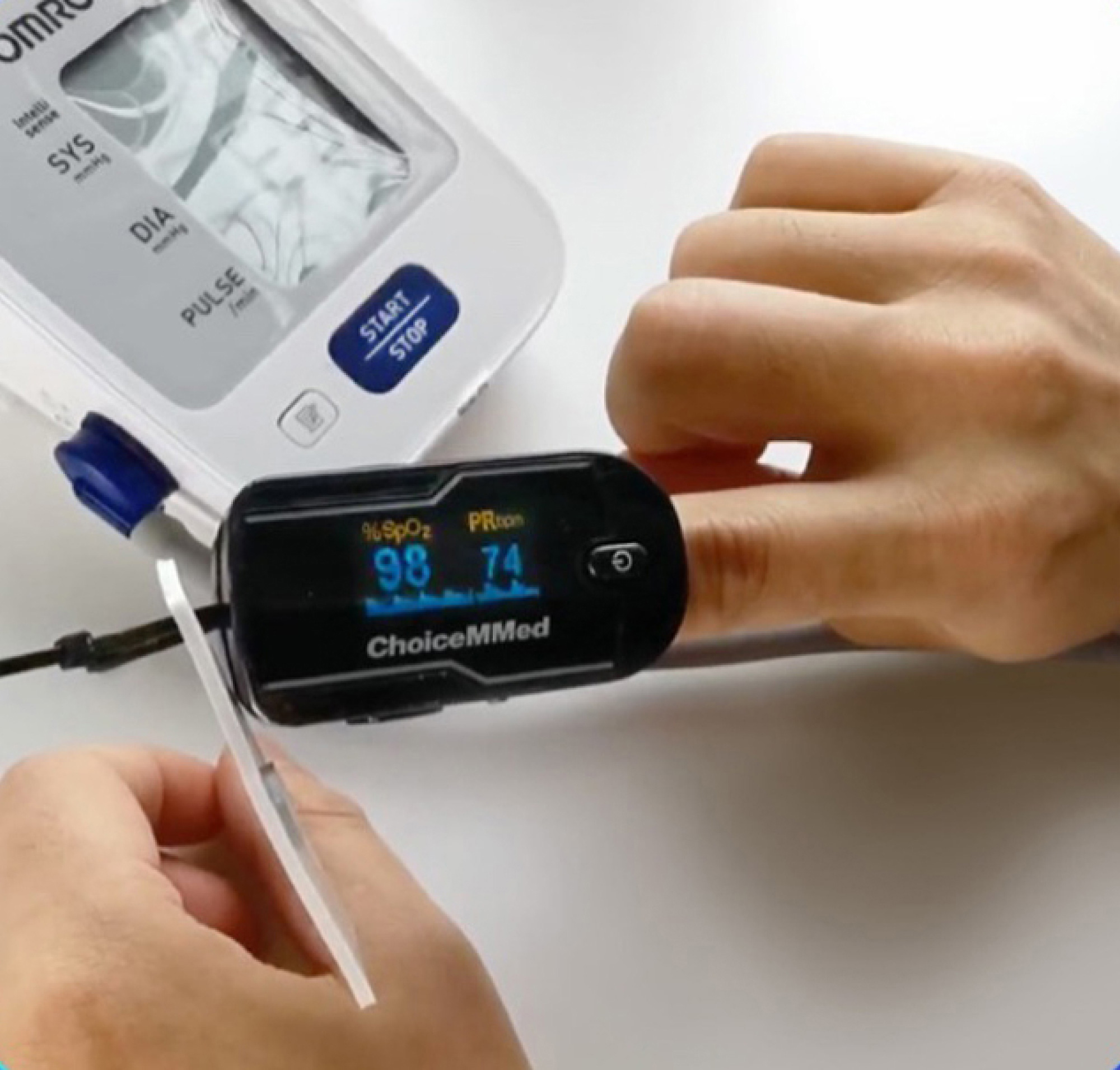 A person uses a fingertip pulse oximeter to measure oxygen saturation and pulse rate, displayed on the device's digital screen.