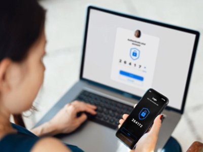 Žena na laptopu koja unosi otp primljen na mobilnom telefonu radi bezbednog prijavljivanja.