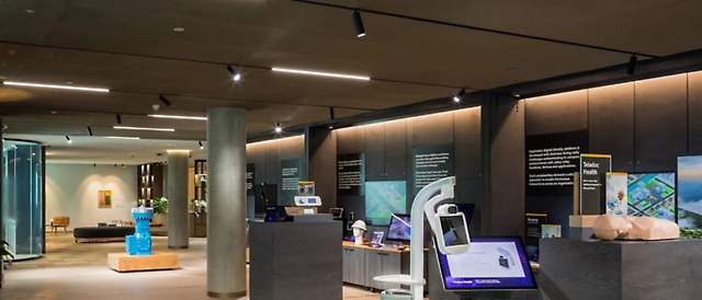 Intérieur d’une exposition d’un musée moderne avec des écrans interactifs, des panneaux d’informations et des éléments de conception minimaliste.
