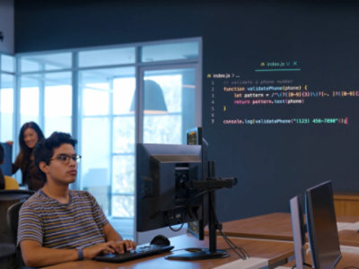 Person sitting at a desk, working on a computer in an office space. 