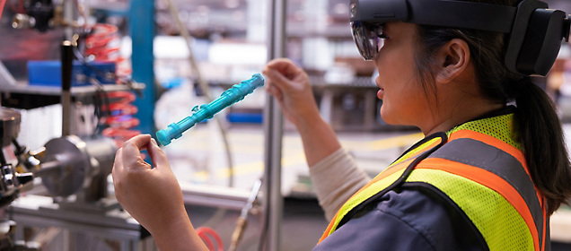 一名身穿安全背心、戴着增强现实眼镜的工人正在检查工业部件。