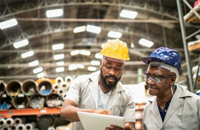 A group of men wearing hard hats looking at a tablet.