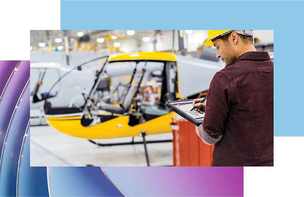 Lucrător inspectând progresul producției de avioane cu o tabletă digitală într-un hangar.