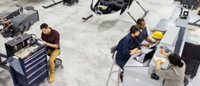 Team of engineers and technicians working on various tasks in an aircraft hangar.