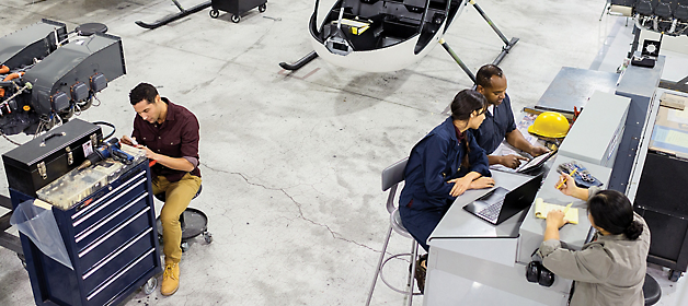 Team of engineers and technicians working on various tasks in an aircraft hangar.