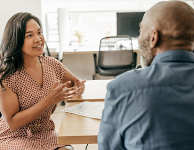 A woman and man sitting at a table talking.