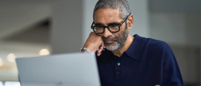 Person seated at a desk, focusing on a laptop screen.