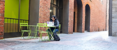 Muškarac sa tri psa stoji za pultom u prodavnici za kućne ljubimce i razgovara sa blagajnicom. Iza pulta se nalaze police 