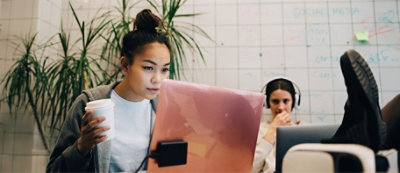 שני אנשים עובדים עם מחשבים נישאים במשרד מודרני. אדם אחד מחזיק ספל קפה