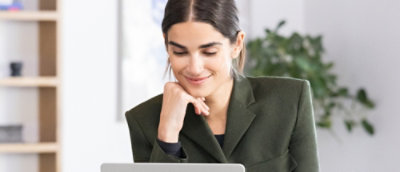 Une femme souriant, travaillant sur un ordinateur portable