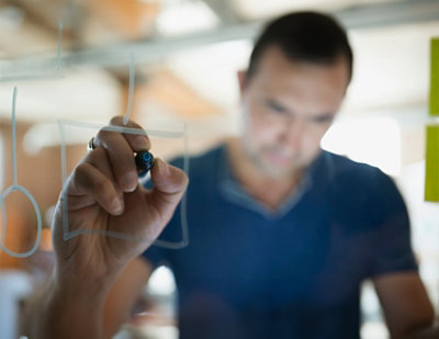 A hand writing on a glass board.