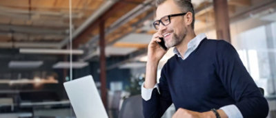 A man speaking in phone and looking into laptop.