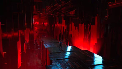 A silhouette walks down a narrow pathway, illuminated by red light.