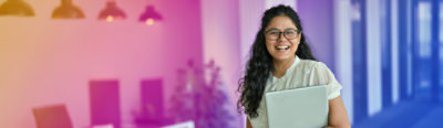 A person wearing a white short sleeved shirt and holding a laptop, smiling, image with coloured gradient background.