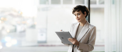  A person wearing a suit jacket, holding a Surface device and a pen.