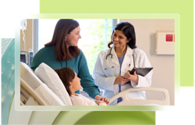 A woman in a white coat holds a clipboard while standing near a hospital bed with a child.
