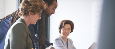 A man showing something on screen to office people.