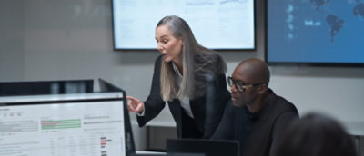 A women speaking someone and a man working in laptop.