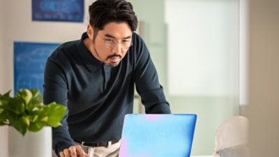 A person sitting at a table looking at a laptop.