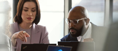 Two people discussing and working on laptop