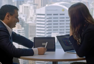 Two people discussing and working on laptop