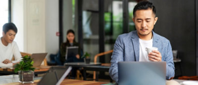 A men looking into laptop with a cup in hand