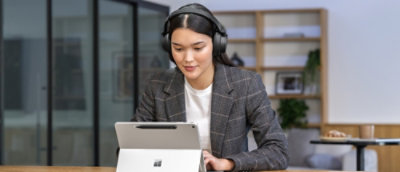 A women looking in to a laptop wearing headphones