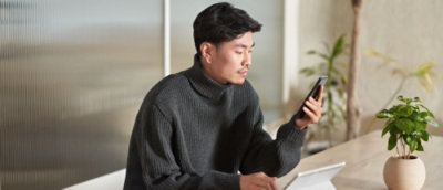 A man sitting at a desk using a cell phone.