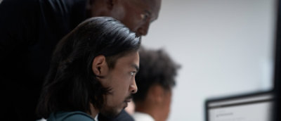 A close-up of a man's face with long hair and a mustache.