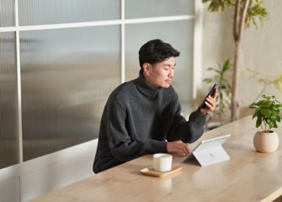 A person sitting at a table with a cup and a tablet.