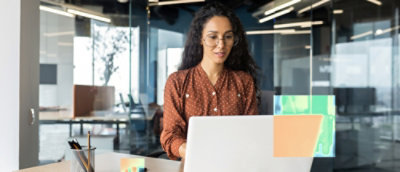 A woman in a red shirt and glasses using a laptop.