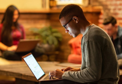 A man with spectacles working on his tablet.