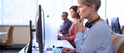 A woman wearing a headset looking at a computer screen.