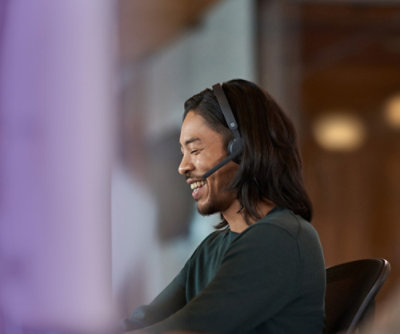 Usmívající se osoba s nasazenou náhlavní soupravou