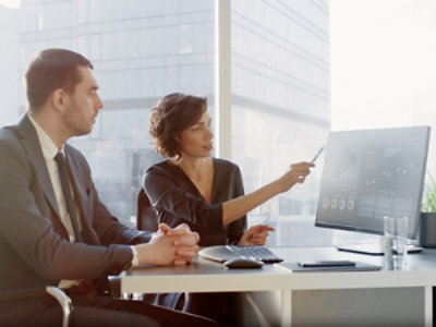 Žena , která sedí vedle muže a ukazuje na obrazovku počítače