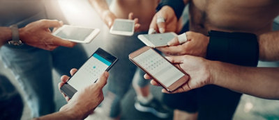 Kilka osób stojących w kręgu i trzymających smartfony wyświetlające aplikacje kalendarza.