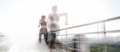 Osoba u sportskoj odeći trči po krovu, a u pozadini se vidi pejzaž grada,