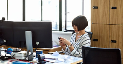 A person sitting at a desk looking at her phone