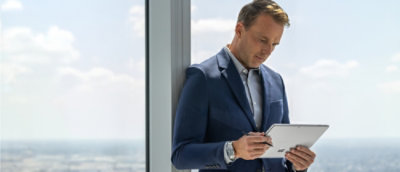 Person standing by a window using a tablet device.