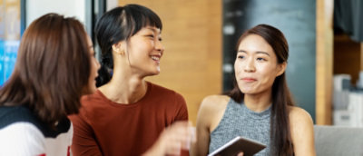 three people discussing while looking at the mobile and smiling