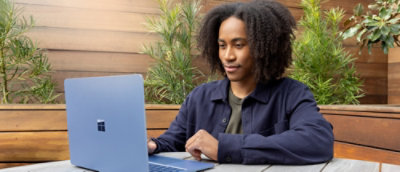 A man with curly hairs working on the laptop in an open environment