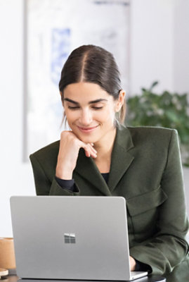 A woman wearing black coat sitting in front of laptop and smiling
