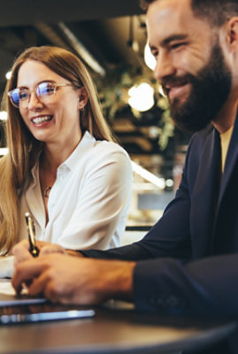 A man and a woman smiling while looking at the laptop