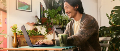 A person sitting at a table with a laptop and a cup of coffee.