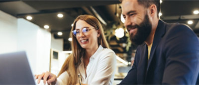A person and another person smiling and working on laptop